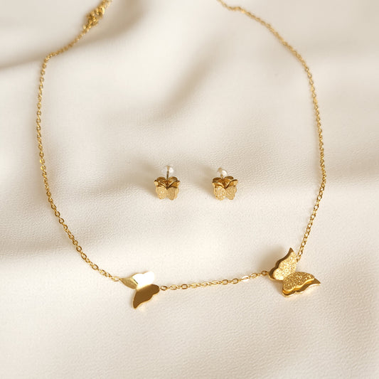 Gold-tone Sparkling Butterfly Set with a two-butterfly necklace and matching textured butterfly stud earrings on cream fabric.
