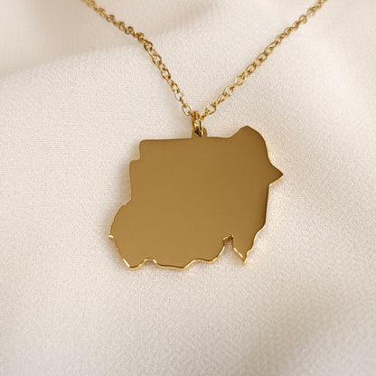 Gold-tone Sudan map pendant necklace displayed at an angle.
