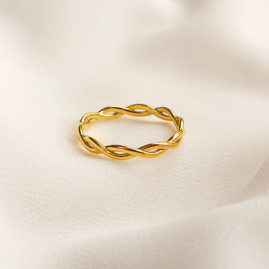 Gold-tone Twisted Chain Ring with an intertwined openwork band on cream fabric.
