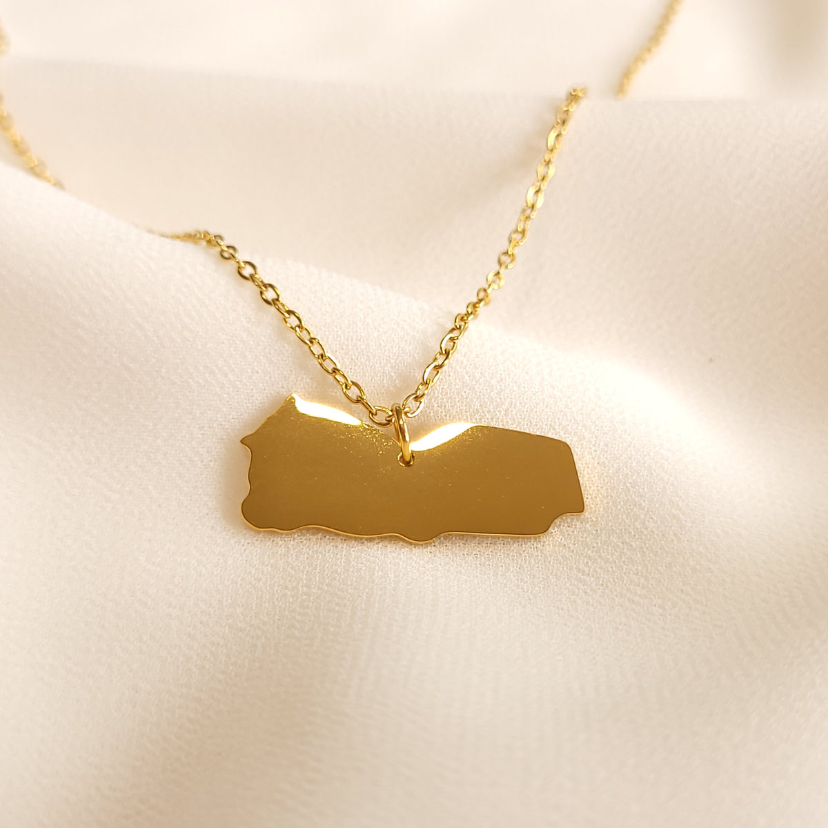 Gold-tone Yemen map pendant necklace with a polished silhouette.
