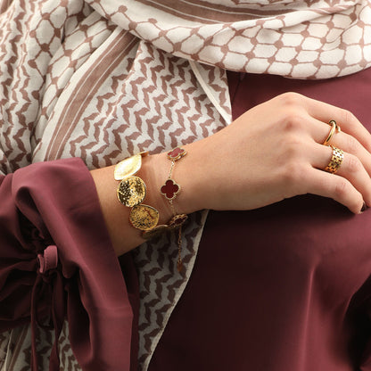 Gold Bold Disc Cuff worn on a model’s wrist alongside a clover bracelet.