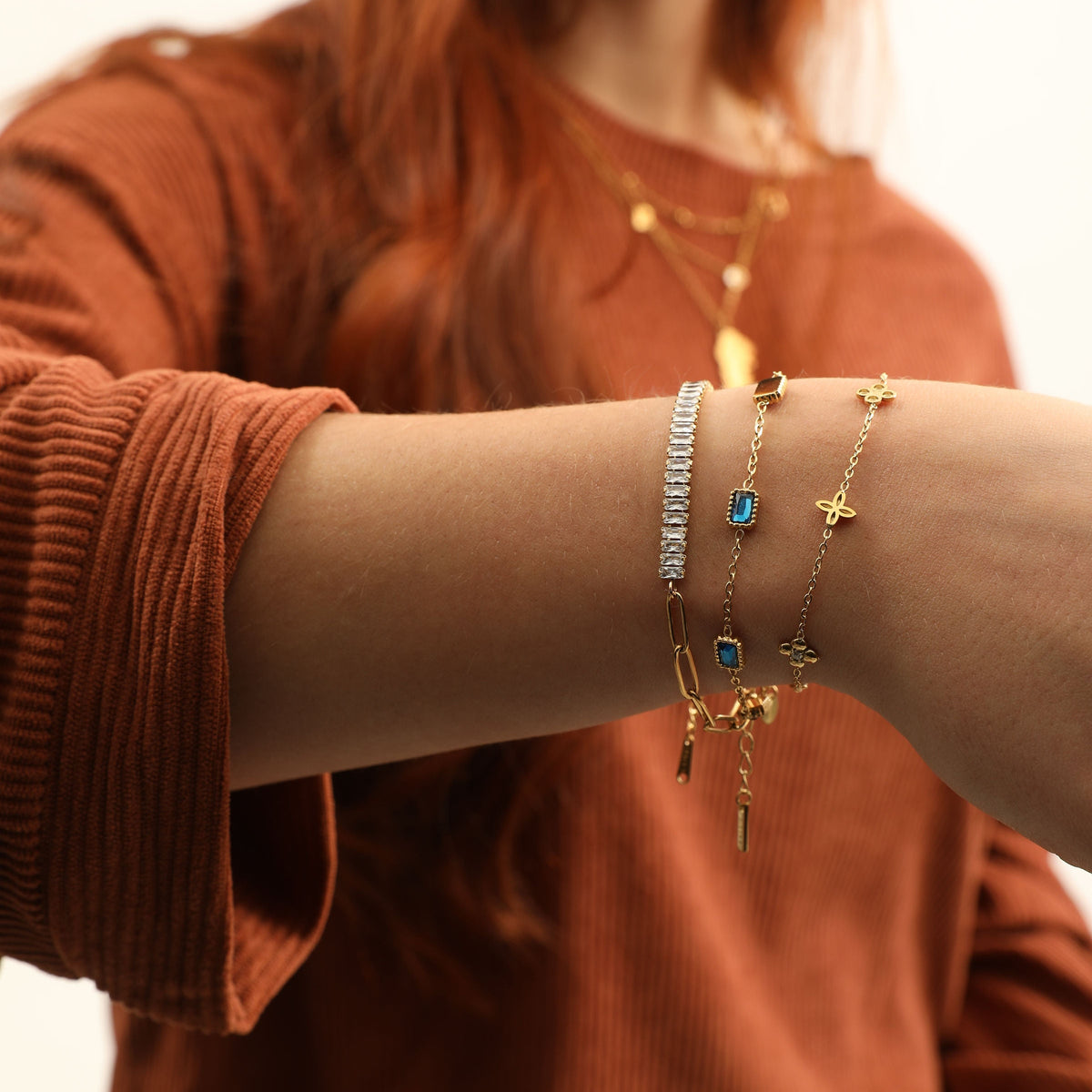 Gold Dainty Flower Bracelet stacked with a blue stone bracelet and a clear stone chain bracelet