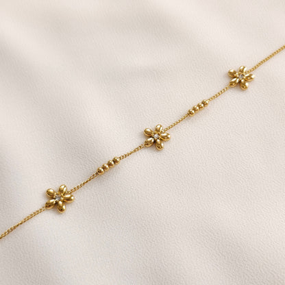 Gold Daisy Chain Bracelet laid straight, showing three polished flowers with clear centres along a fine chain.