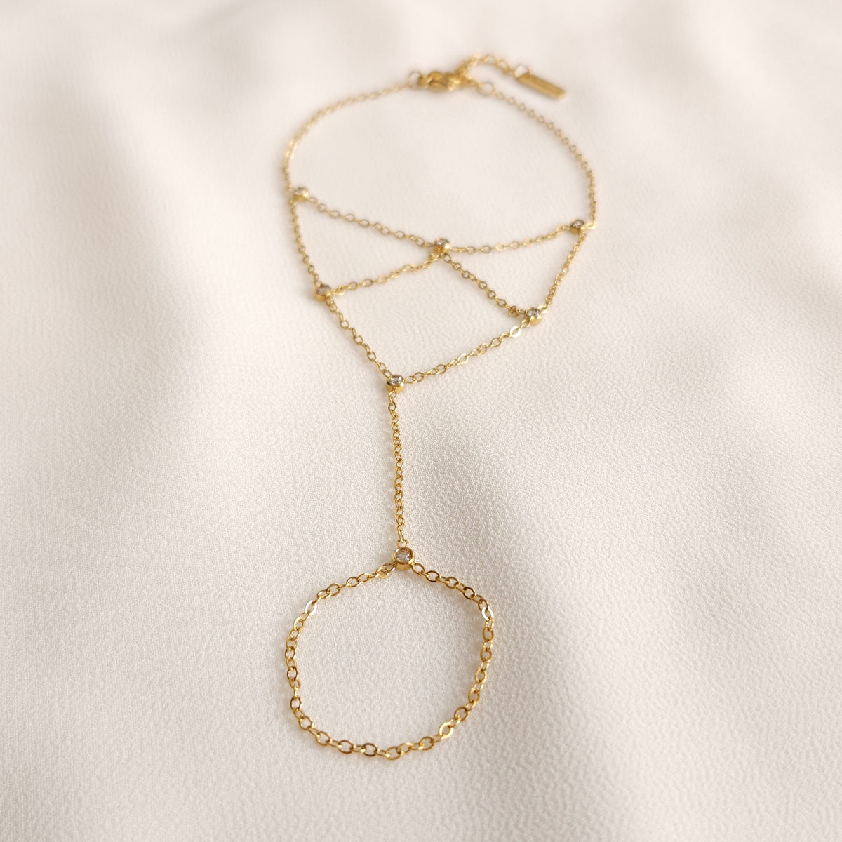 Gold Mesh Hand Chain with a geometric chain web, small clear stones and a connected finger loop.