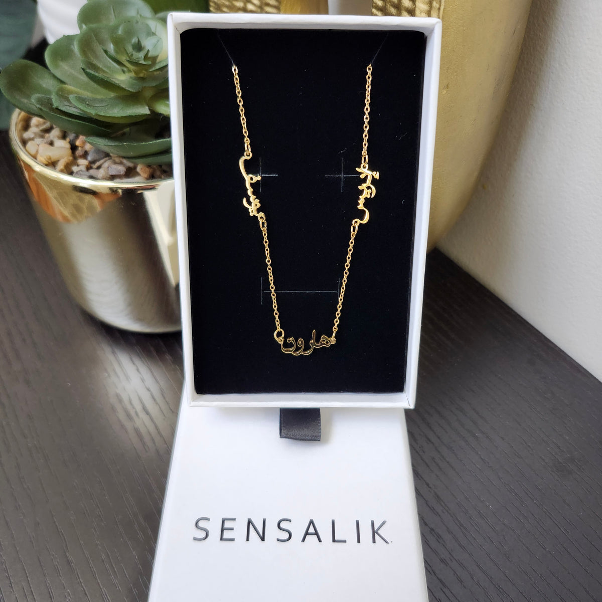 Gold Multiple Name Necklace with three Arabic nameplates displayed in a Sensalik gift box.
