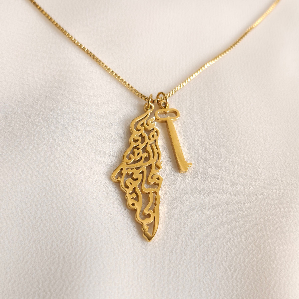 Gold Palestine Calligraphy & Key Necklace with an Arabic calligraphy map pendant and a separate key charm.