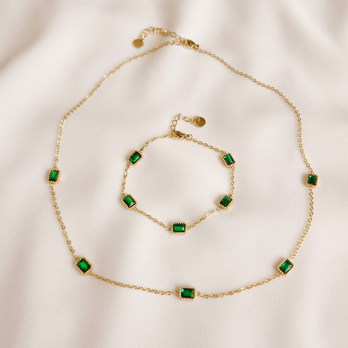 Gold Satellite Emerald Bracelet and matching necklace with rectangular green stones in beaded settings.
