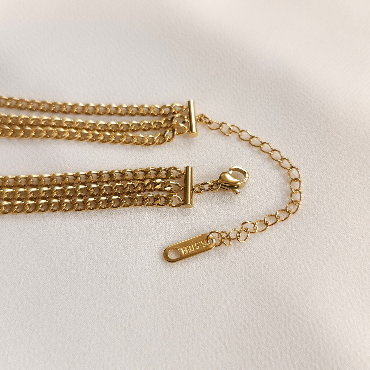 Gold Trio Link Bracelet showing the lobster clasp, adjustable extension chain and end tag.