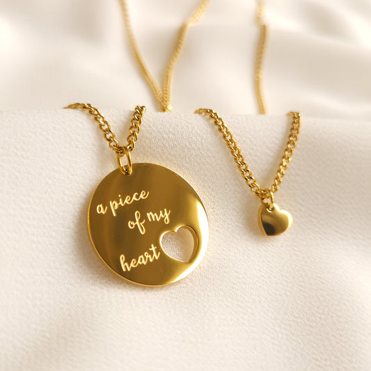Gold necklace set featuring an ‘a piece of my heart’ disc with a heart cutout and a matching small heart pendant.