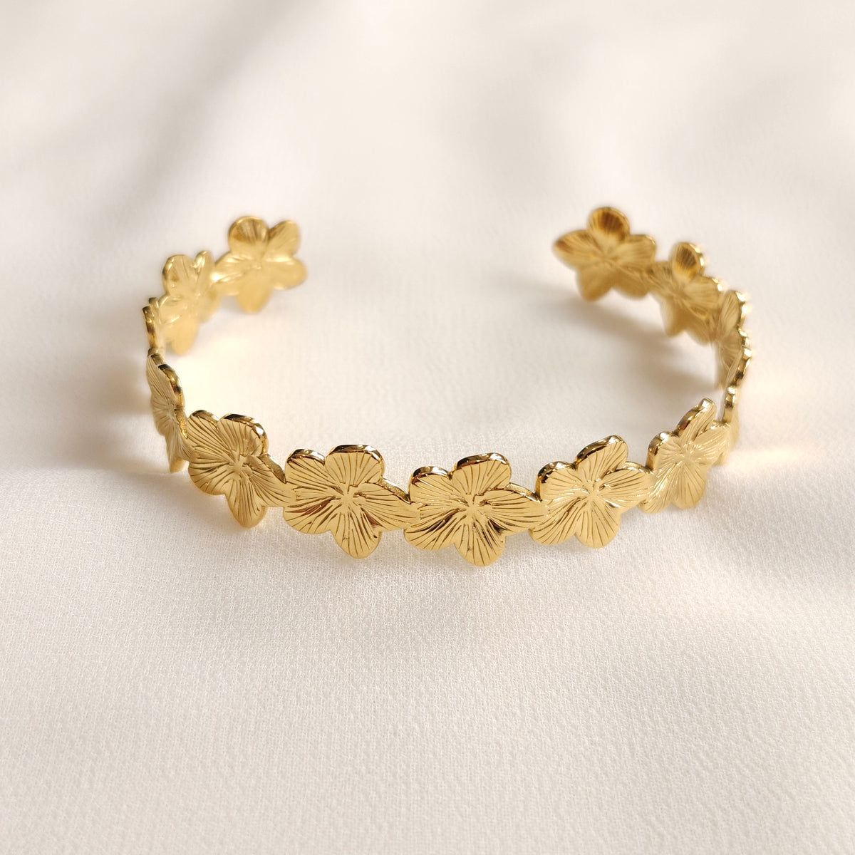 Gold open-ended Flower Cuff with a continuous row of five-petal flowers and engraved petal details.