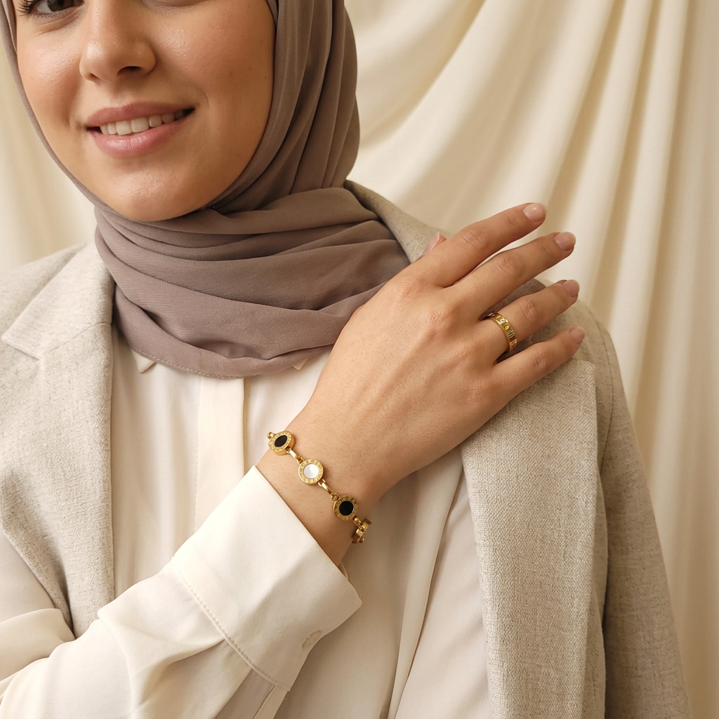 Model wearing the gold-tone Roman Numeral Link Bracelet with a matching band ring, taupe headscarf and cream outfit.
