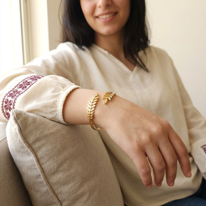 Model wearing the gold Leaf Cuff, showing its leafy branch ends across the wrist.
