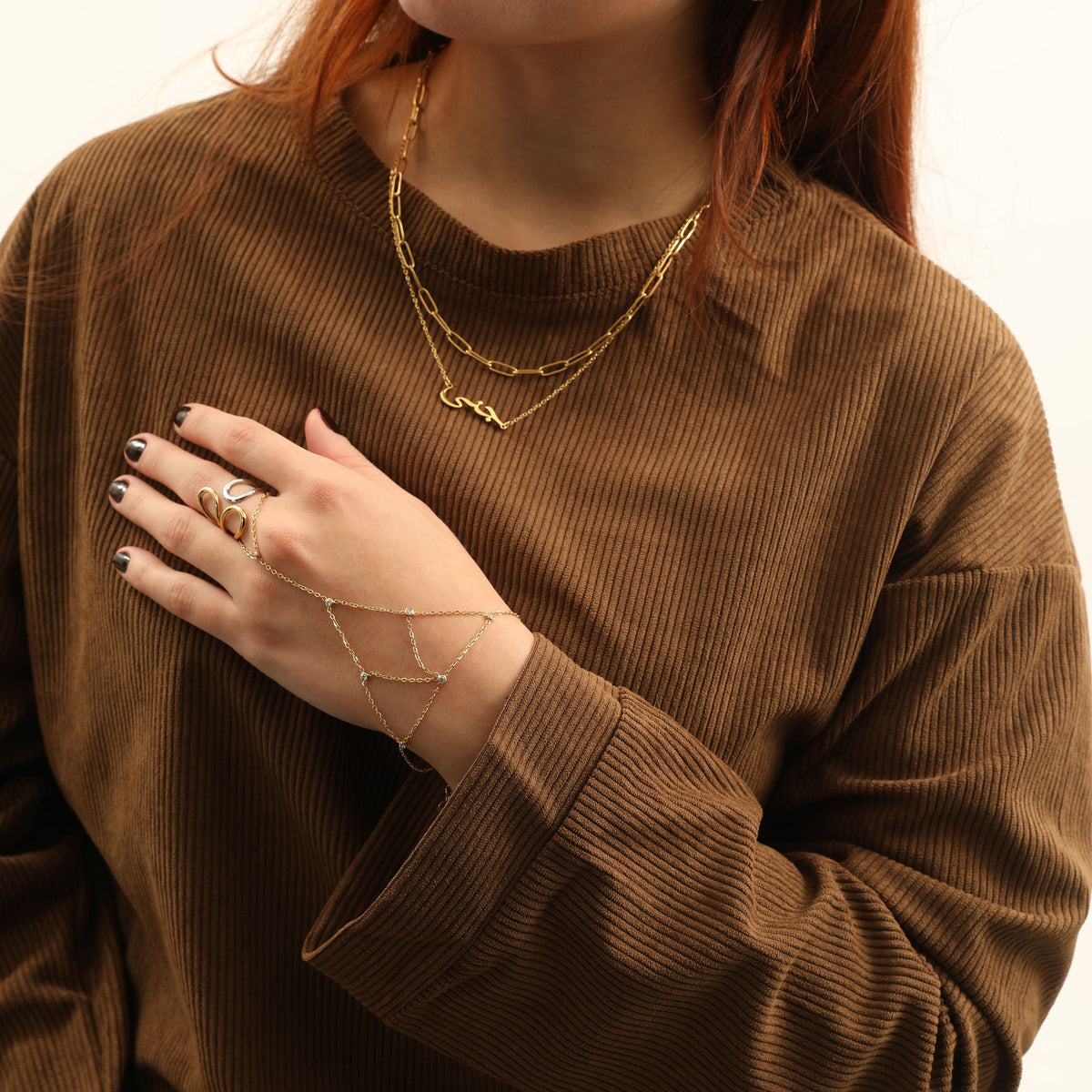 Model wearing the gold Mesh Hand Chain alongside rings and layered gold necklaces.