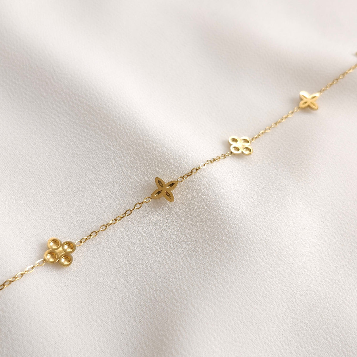 Reverse side of the gold Dainty Flower Bracelet showing the backs of its alternating floral charms.