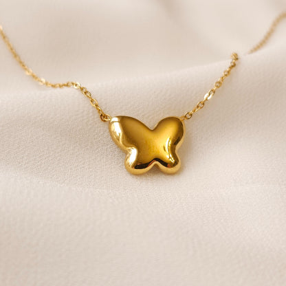 Reverse view of the Mother of Pearl butterfly pendant showing its smooth gold back and fine chain.
