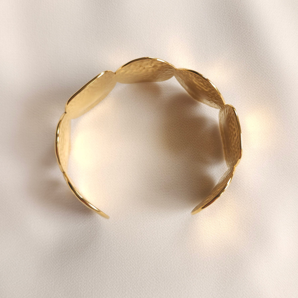 Top view of the gold Bold Disc Cuff showing its curved shape and open ends.