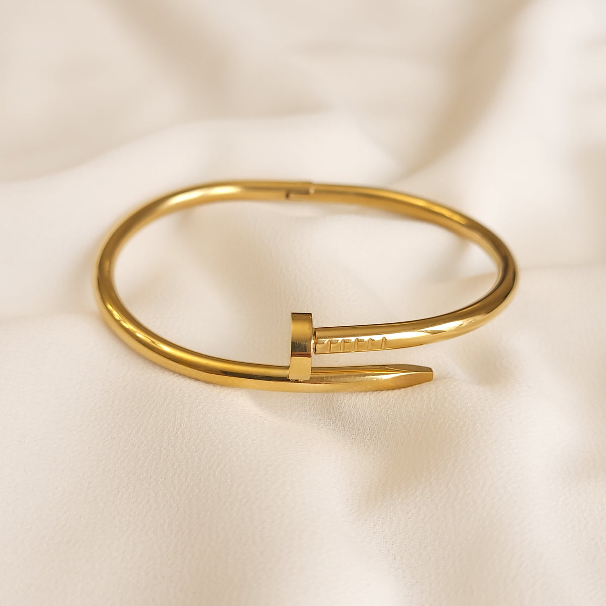 Twisted Nail Bangle in gold tone, showing the overlapping nail head and tapered tip with engraved line details.