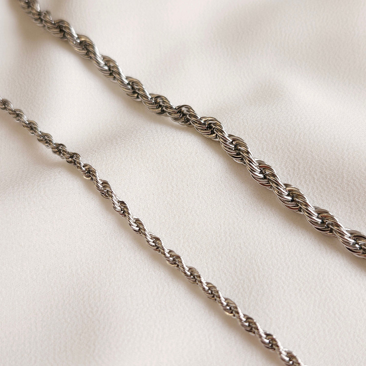 Two silver-tone rope chains shown side by side, comparing their widths and twisted link patterns.