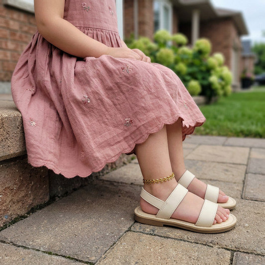 Girl wearing the gold Leaf Anklet with a full floral dress and sandals in a Canadian garden