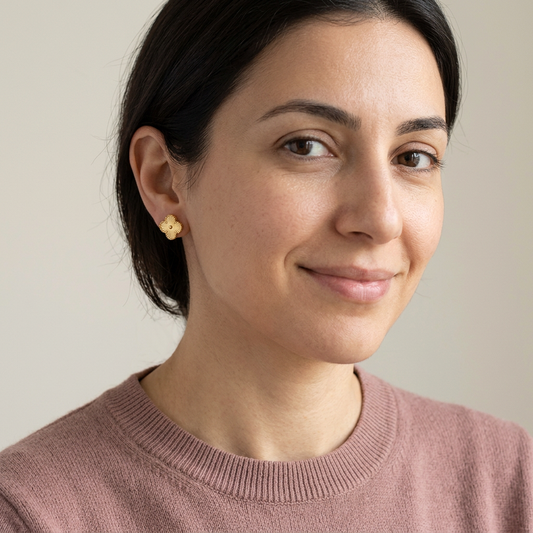 Model in a casual sweater wearing gold clover stud earrings