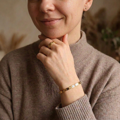 Model wearing a smaller gold stud earring, gold ring and bangle