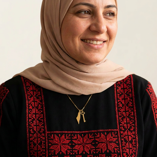 Palestinian model wearing the gold map-and-key necklace against a warm ivory studio backdrop