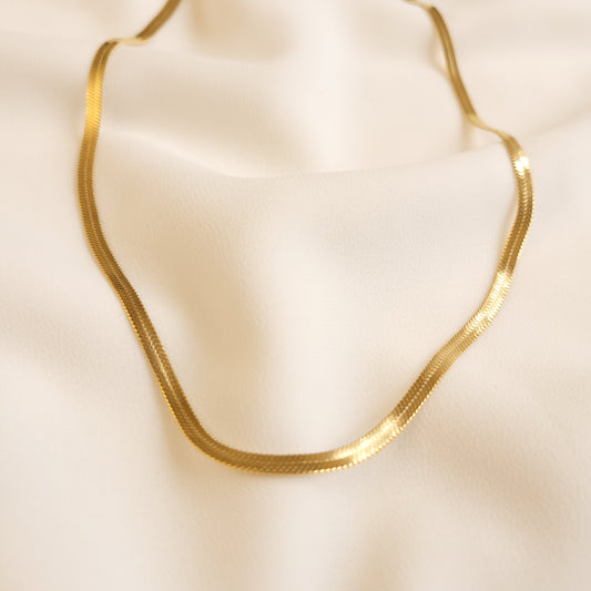 Classic Herringbone Necklace in gold tone, showing its flat woven links and smooth, reflective surface.