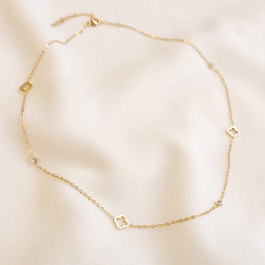 Dainty Clover Necklace in gold tone arranged in a loop, featuring open clover charms alternating with small clear stones on a fine chain.