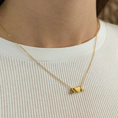 Letter Add-On S and L charms separated by a gold-tone heart, worn on a fine chain over a white ribbed top.
