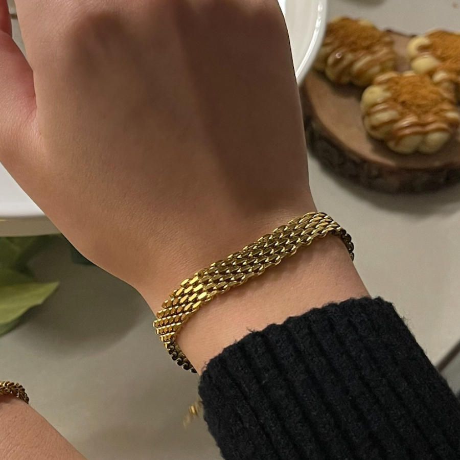 Mesh Belt Bracelet worn on a wrist, showing its flat woven profile beside a black sleeve.