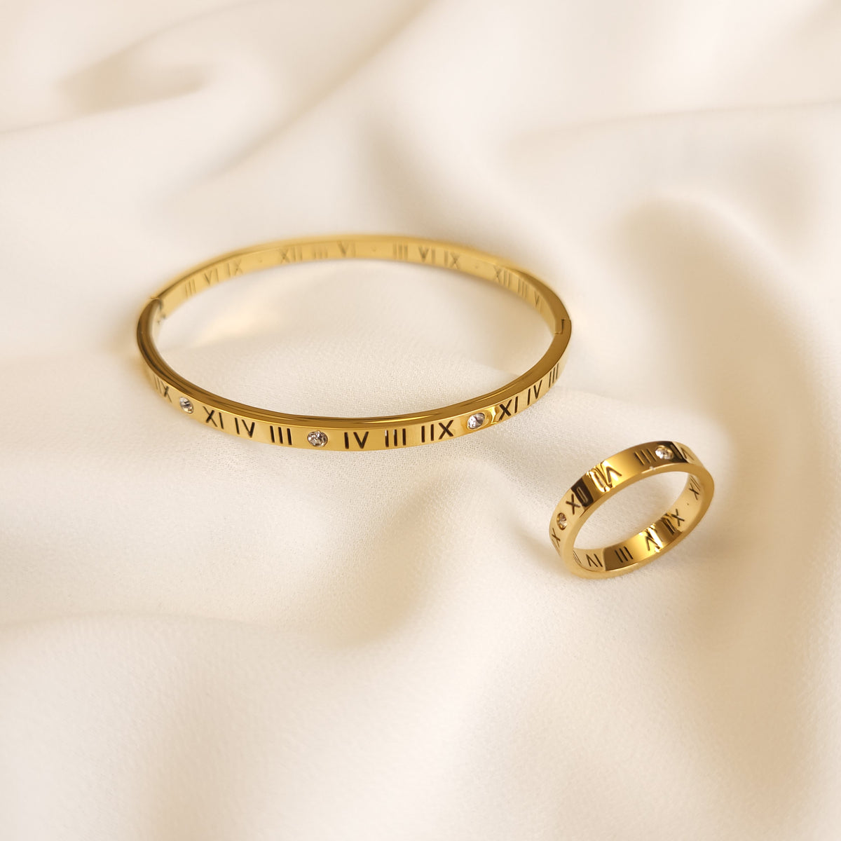 Roman Numeral Band Ring displayed beside a matching gold-tone bangle, both featuring engraved numerals and clear stone accents.