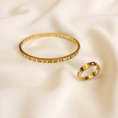 Roman Numeral Band Ring displayed beside a matching gold-tone bangle, both featuring engraved numerals and clear stone accents.