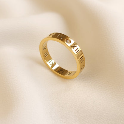 Roman Numeral Band Ring in gold tone, displayed upright to show the engraved numerals and round clear stone accents.