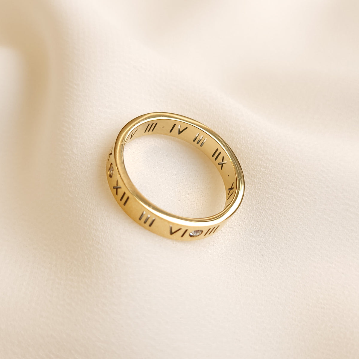 Roman Numeral Band Ring in gold tone viewed at an angle, showing the engraved numerals around the band and polished inner surface.