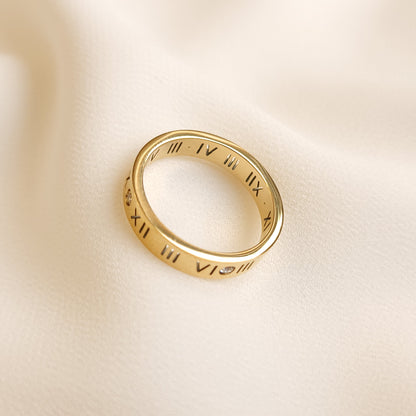 Roman Numeral Band Ring in gold tone viewed at an angle, showing the engraved numerals around the band and polished inner surface.
