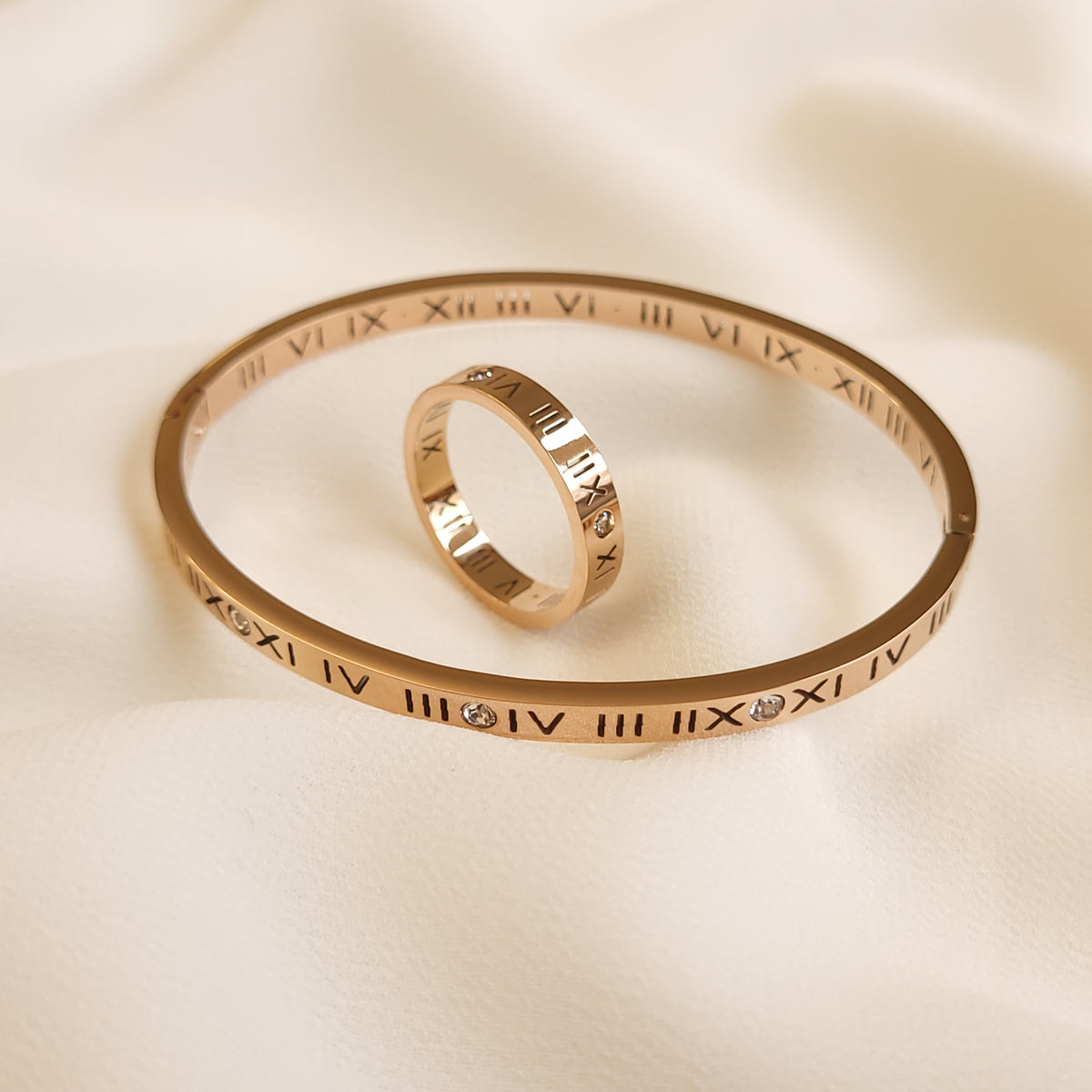 Roman Numeral Band Ring in rose gold tone displayed upright inside a matching Roman numeral bangle.