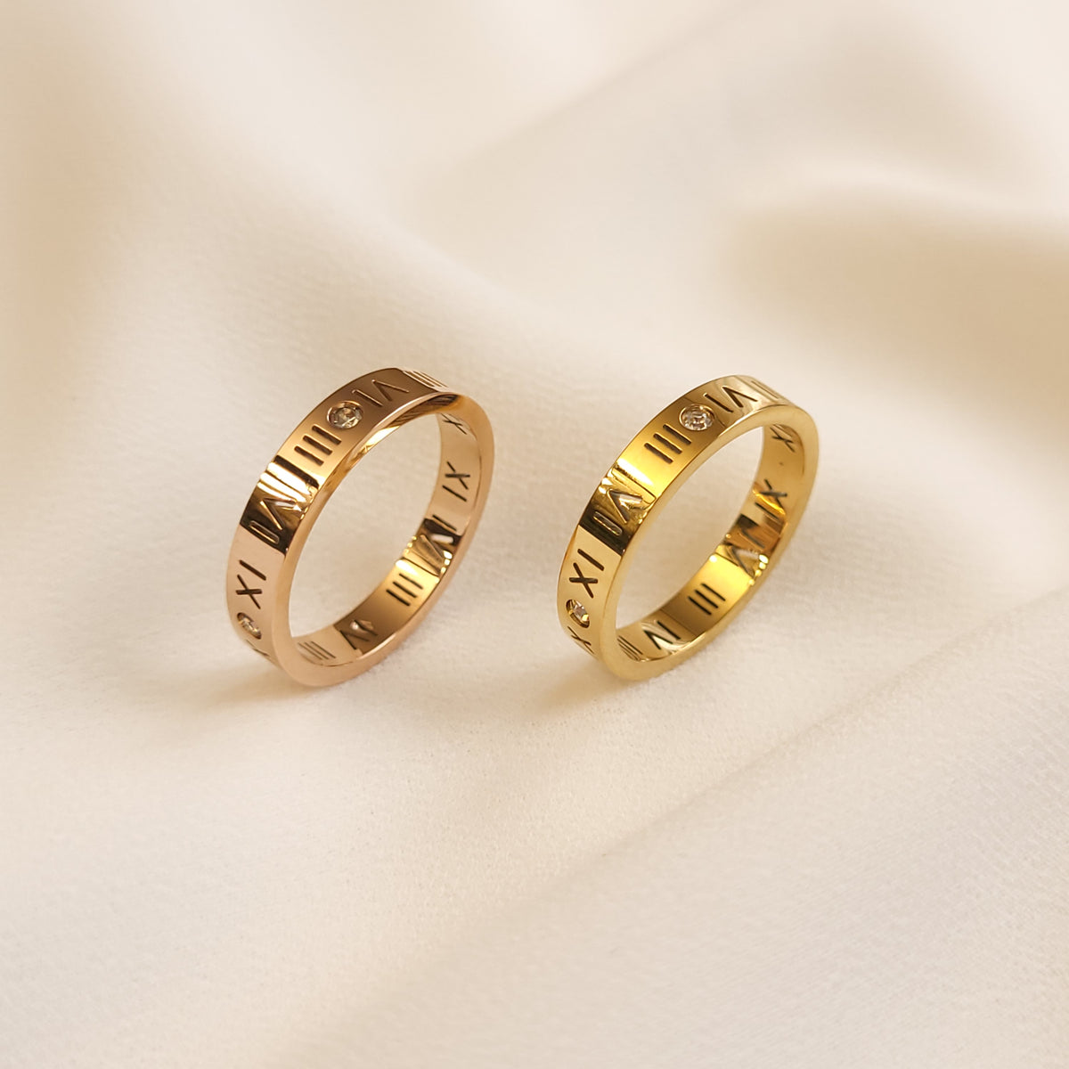 Roman Numeral Band Rings in rose gold and gold tones displayed upright side by side to compare their finishes.