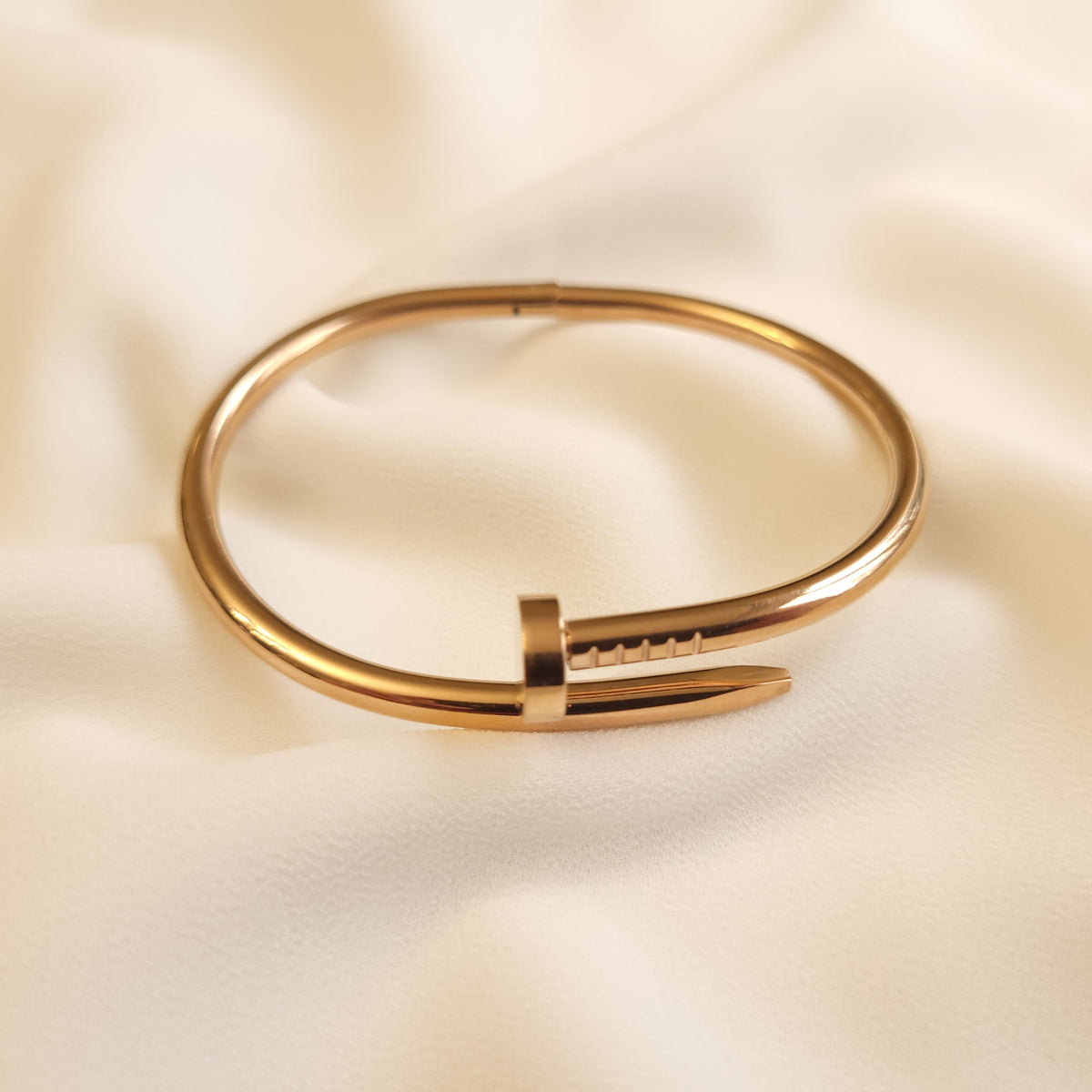 Twisted Nail Bangle in rose gold tone, showing the polished band, nail head, and pointed tip.