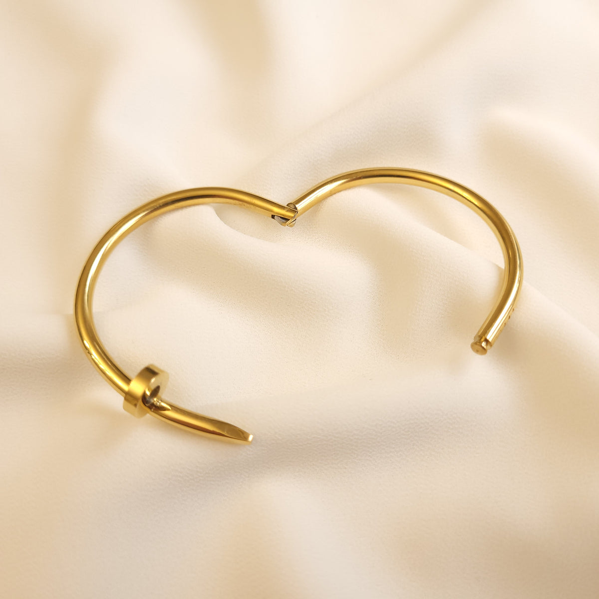 Twisted Nail Bangle shown open, revealing the hinged design and nail-shaped ends.